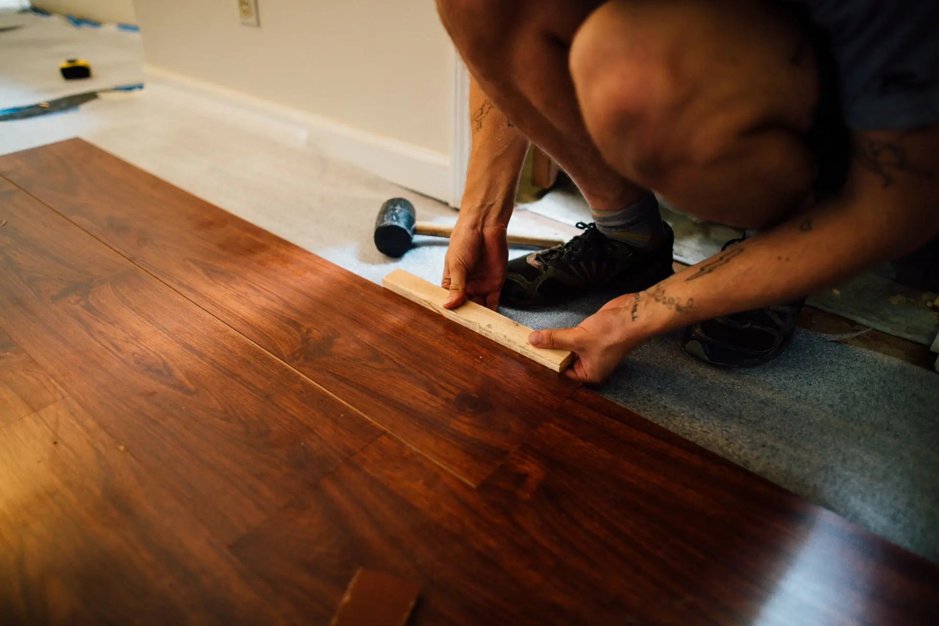 Installer fitting a dark walnut timber plank during a flooring installation